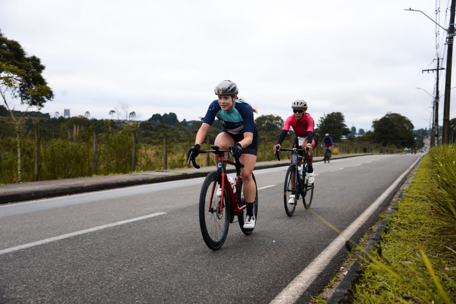 Ciclistas competem em uma prova de ciclismo em uma via urbana.