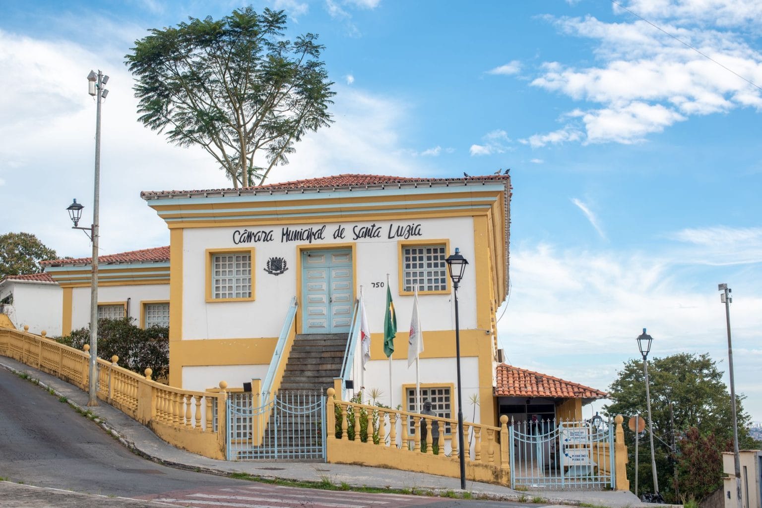Fachada histórica de uma Câmara Municipal sob céu azul, com árvores ao redor.